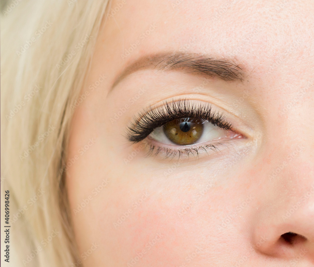 Obraz premium Eyelash Extension Procedure. Woman Eye with Long Blue Eyelashes. Close up, selective focus.