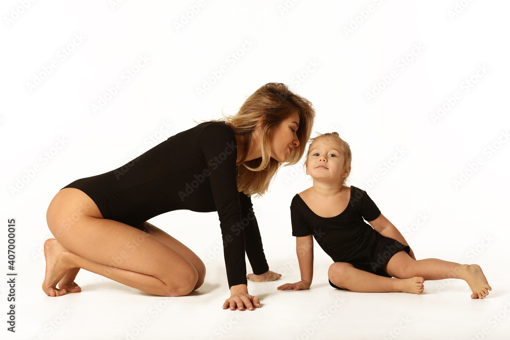 Obraz premium cute baby girl and mum in black bodies having fun full body studio portrait isolated on white