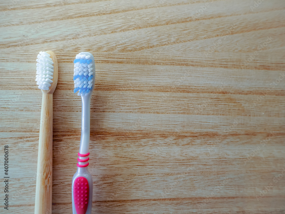 Plastic free lifestyle swap concept with a plastic toothbrush and a bamboo toothbrush as sustainable alternative on a wooden background. Plastic free lifestyle swap concept with a plastic toothbrush and a bamboo toothbrush as sustainable alternative on a wooden background.
