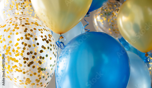 Blue and transparent balloons with golden confetti on the background of a large window. Light interior
