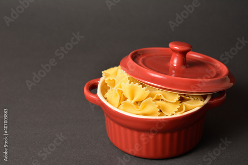 Side view of Cooking pan with cover filled with raw italian farfale pasta on isolated on dark background 
 photo