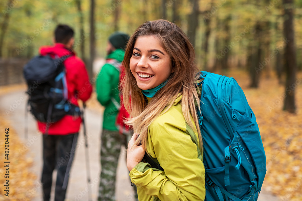 Happy woman walking in autumn forest with friends