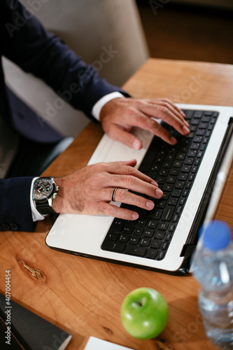 Close up of man`s hand working on laptop. Young businessman using laptop in his office