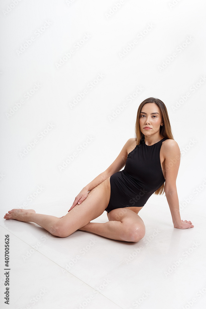 sexy asian woman with long hair posing in black lingerie on white studio background with bare feet. attractive female sitting on floor with her knees bent. model tests of skinny lady in bodysuit sexy asian woman with long hair posing in black lingerie on white studio background with bare feet. attractive female sitting on floor with her knees bent. model tests of skinny lady in bodysuit
