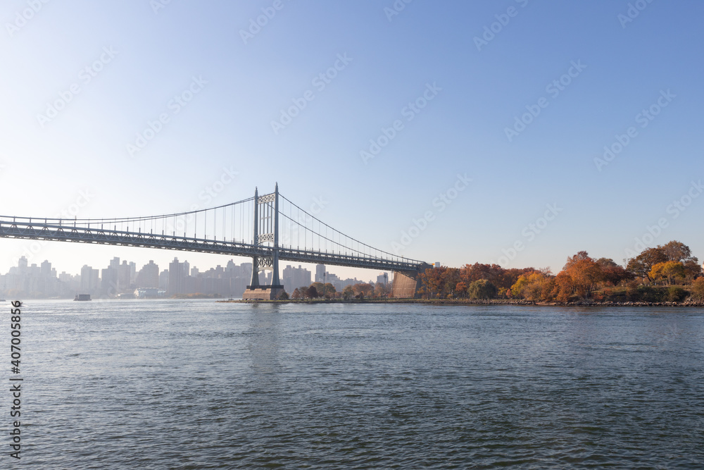 Naklejka premium The Triborough Bridge over the East River with the Shore of Randalls and Wards Islands during Autumn with Colorful Trees in New York City