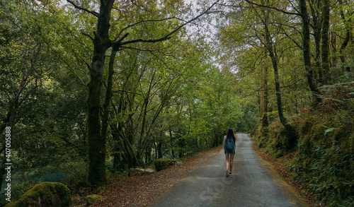 Young woman walking on a path surrounded by forest in summer. Galicia in summer. Santiago's road