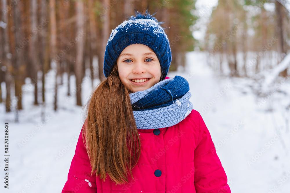 Portrait of a little happy girl in winter in a snow-covered hat who walks in the winter forest Portrait of a little happy girl in winter in a snow-covered hat who walks in the winter forest