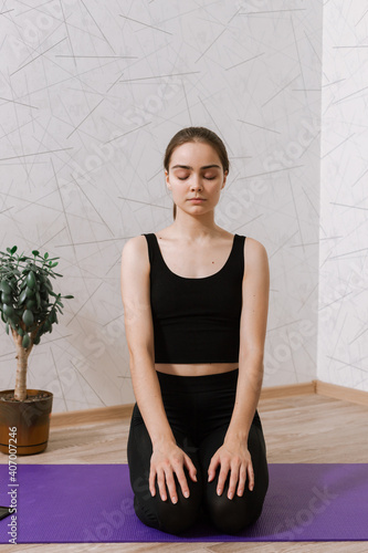 Calm woman meditating on mat at home while sitting in Thunderbolt asana and practicing yoga with closed eyes  photo