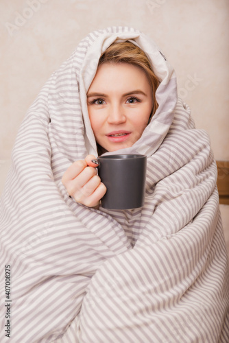 blonde woman in bed with a mug wrapped in a blanket