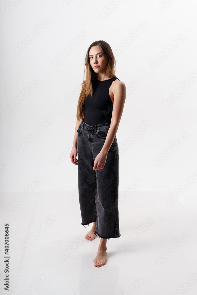 portrait of young attractive asian woman with long hair in black bodysuit, jeans, isolated on white studio background. skinny pretty female posing on cyclorama. model tests of beautiful lady portrait of young attractive asian woman with long hair in black bodysuit, jeans, isolated on white studio background. skinny pretty female posing on cyclorama. model tests of beautiful lady
