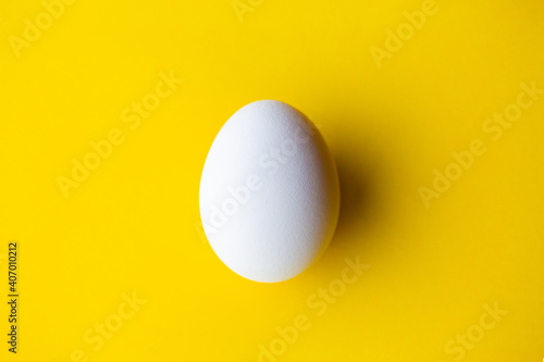White egg on a yellow background. Egg on a yellow background. White egg with shadow. Easter concept. Breakfast food. Ingredient 