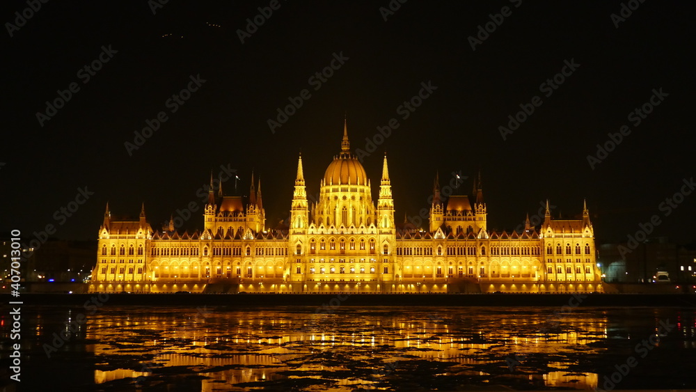 Fototapeta premium Parliament building by night in Budapest. with reflection in the icy river Danube