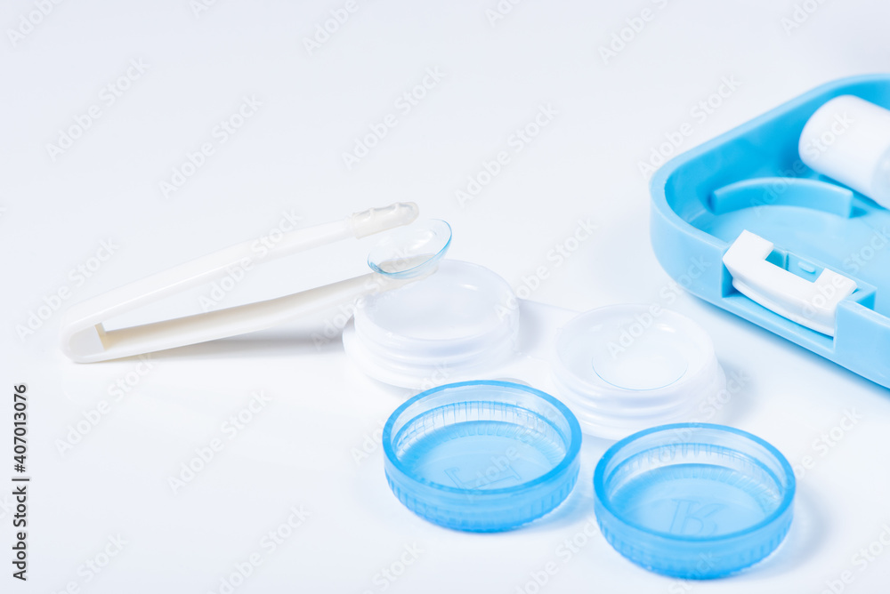 Soft contact lenses with solution, container and tweezers on white background with place for text. Macro photography Soft contact lenses with solution, container and tweezers on white background with place for text. Macro photography