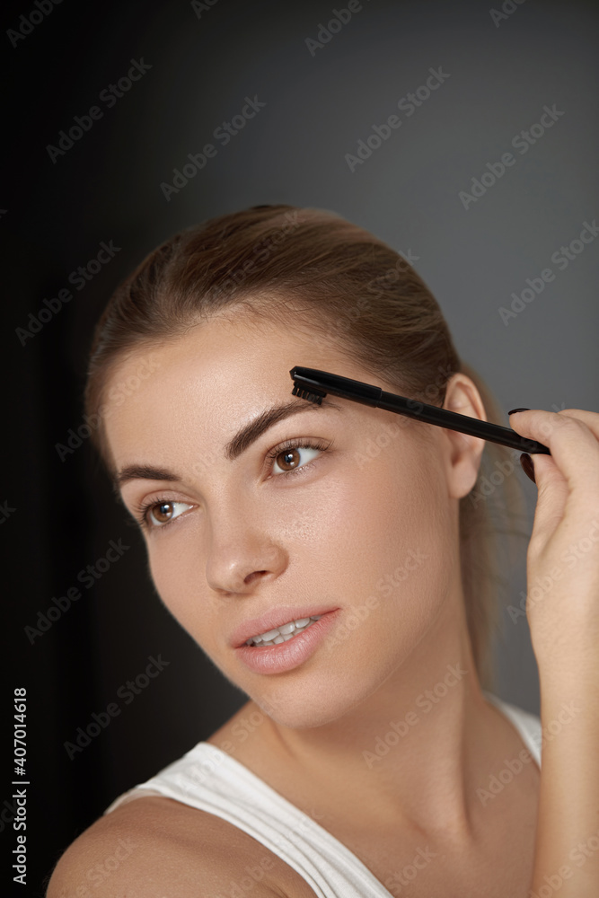 Fototapeta premium Beauty makeup. Woman shaping eyebrow closeup. Girl model with professional makeup contouring eyebrows
