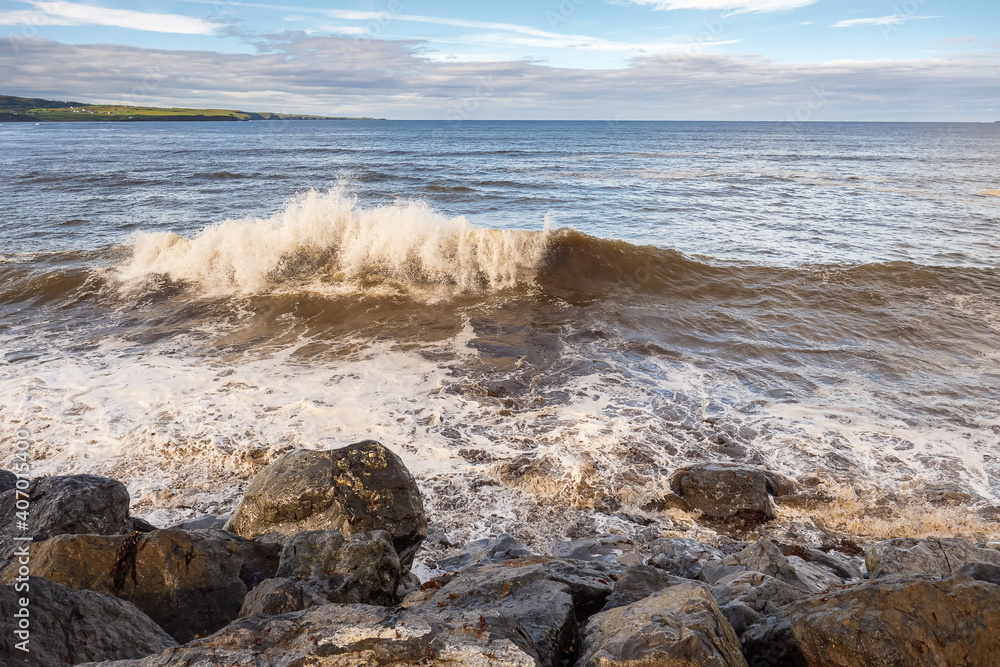Powerful Atlantic ocean wave hit rough stone coast line. Lahinch town, county Clare, Ireland. Warm sunny day, Majestic cloudy sky. Nature seascape. Powerful Atlantic ocean wave hit rough stone coast line. Lahinch town, county Clare, Ireland. Warm sunny day, Majestic cloudy sky. Nature seascape.