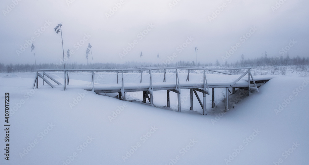 Frozen bridge in the winter forest after a snowfall with snowdrifts