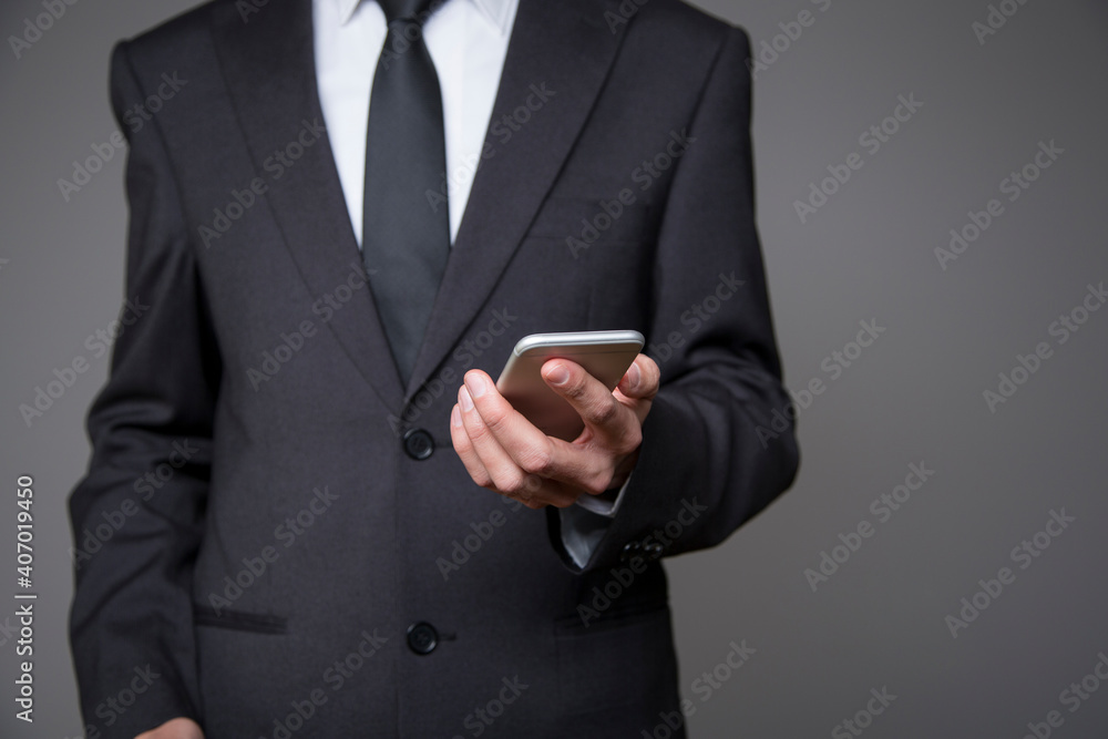 businessman in gray suit with mobile phone in hand on gray background businessman in gray suit with mobile phone in hand on gray background