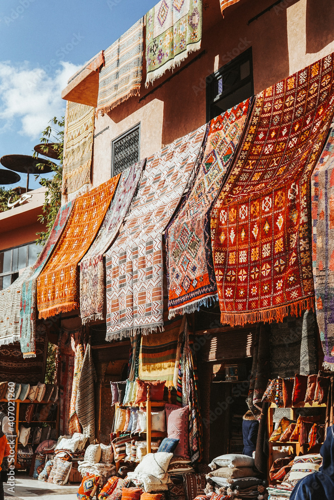 Blick auf handgefertigte Teppiche, in einer Reihe platziert. Einkaufserlebnis am Souk von Marrakesch, Marokko. - obrazy, fototapety, plakaty 