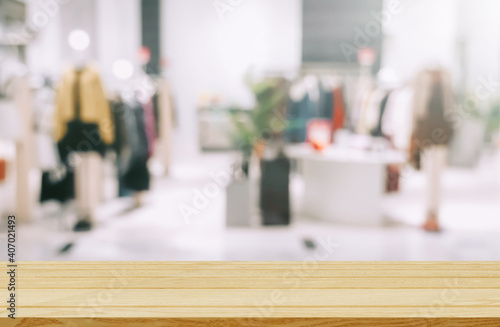 Empty brown wooden table and De focused blurry background of clothing store with bokeh image luxury and fashionable brand for display or montage your products