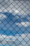 Chain link fence against a cloudy sky