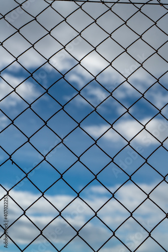 Chain link fence against a cloudy sky