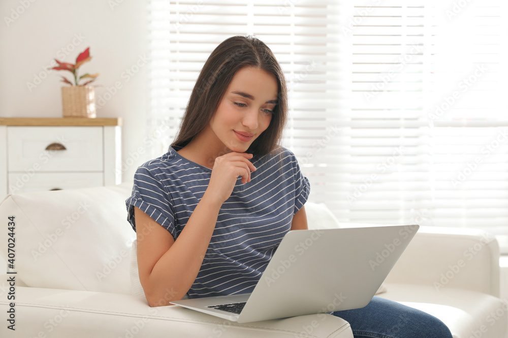 Young woman using laptop for search on sofa at home Young woman using laptop for search on sofa at home