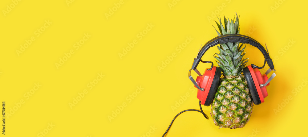 pineapple in red retro headphones on a yellow background pineapple in red retro headphones on a yellow background