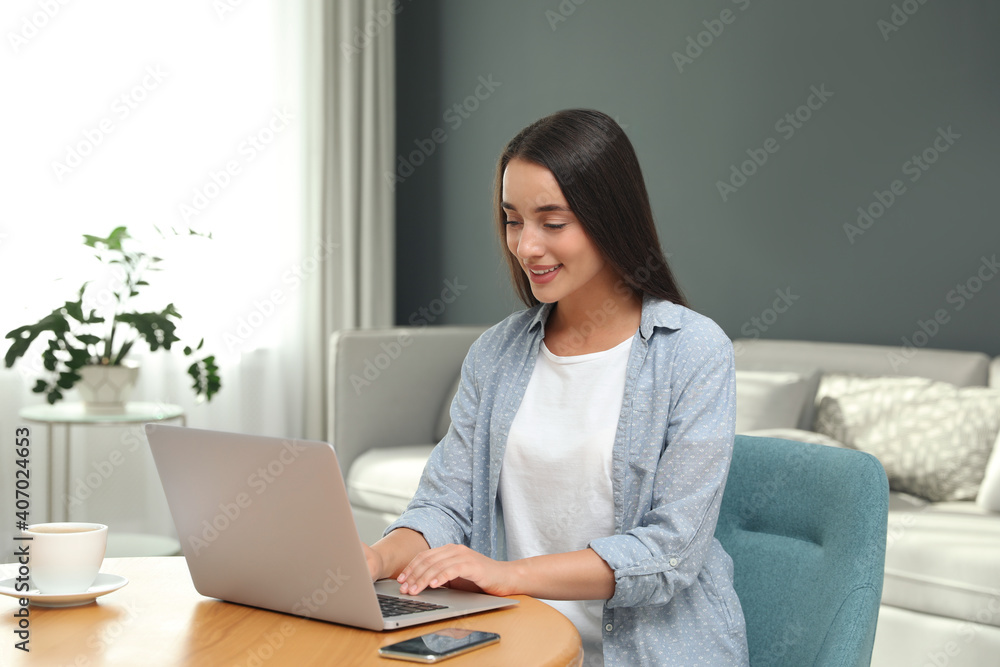 Young woman using laptop for search at wooden table in living room Young woman using laptop for search at wooden table in living room