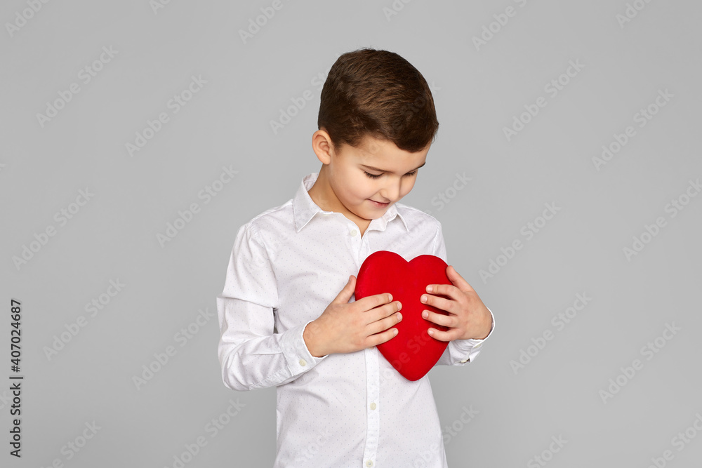 valentine's day. cute little child boy holding red heart isolated on gray background valentine's day. cute little child boy holding red heart isolated on gray background
