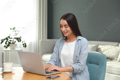 Young woman using laptop for search at wooden table in living room