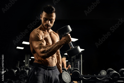 Muscular bodybuilder training biceps with dumbbell. photo