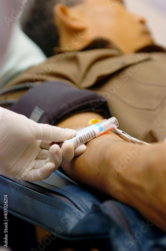 Unidentified medicall staff  hand with protective glove checking transfusion label during blood donor charity.