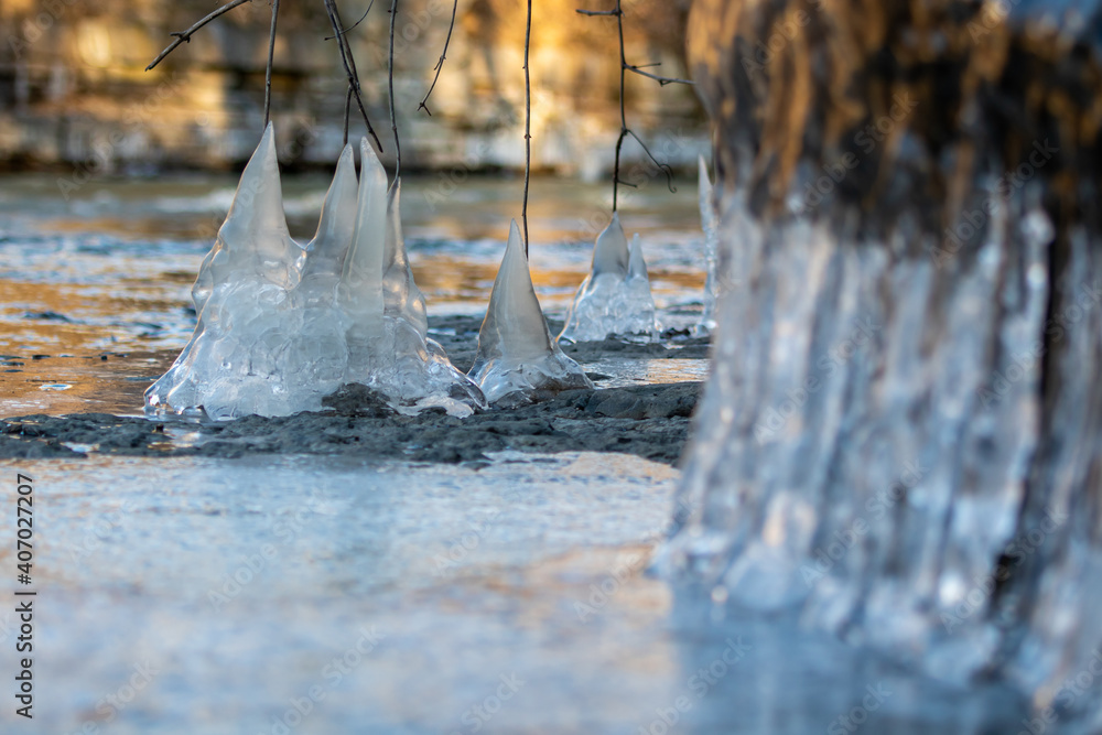 Close-up of icicles hanging from roots, branches and rocks that formed next to a stream.