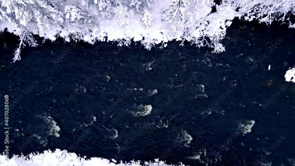 Top down view of a cold river flowing through a snow covered woodland in the wild. Top down view of a cold river flowing through a snow covered woodland in the wild.