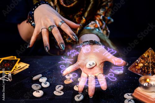 Obraz na płótnie The fortune teller holds a rune with a luminous astrological circle above it in the palm of her hand