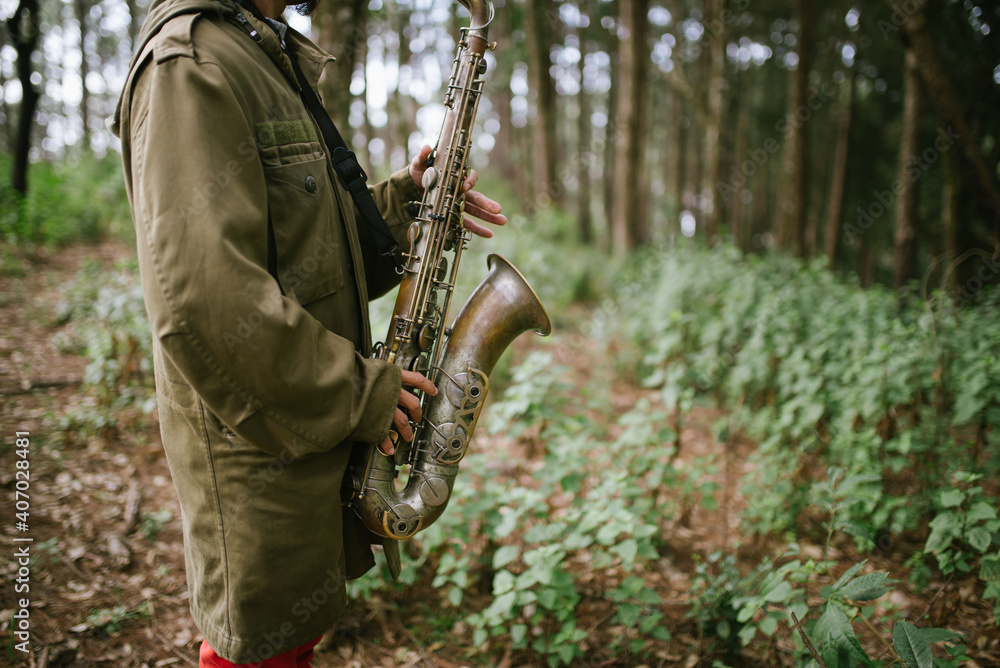 A hand held saxophone in the forest bokeh background