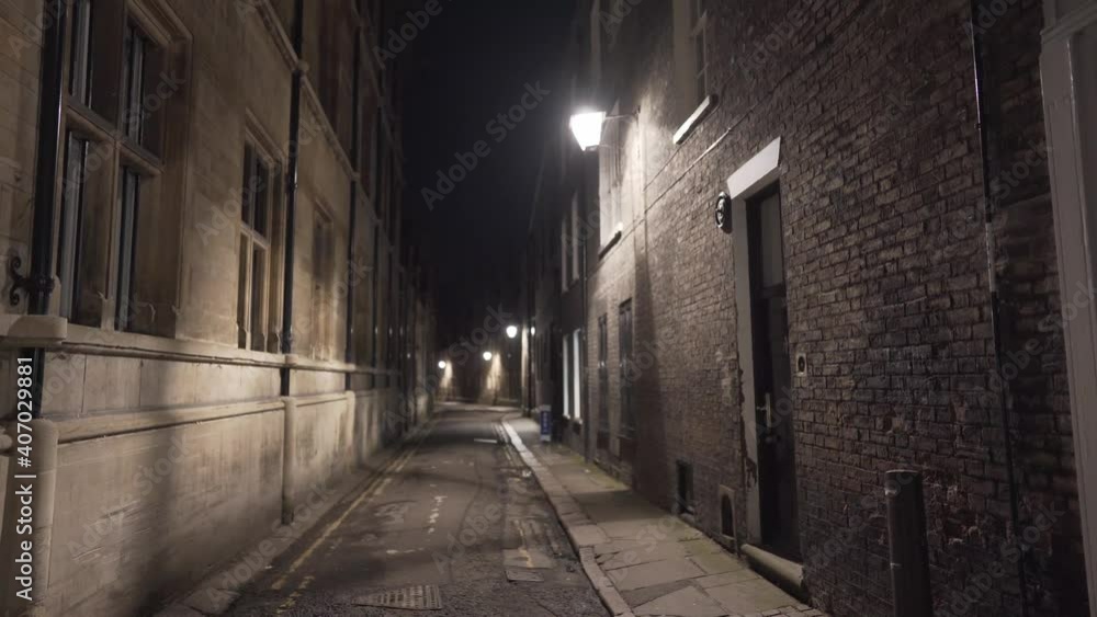 Narrow street alley illuminated in cambridge city centre england uk. Scary passage with yellow light during the night Narrow street alley illuminated in cambridge city centre england uk. Scary passage with yellow light during the night