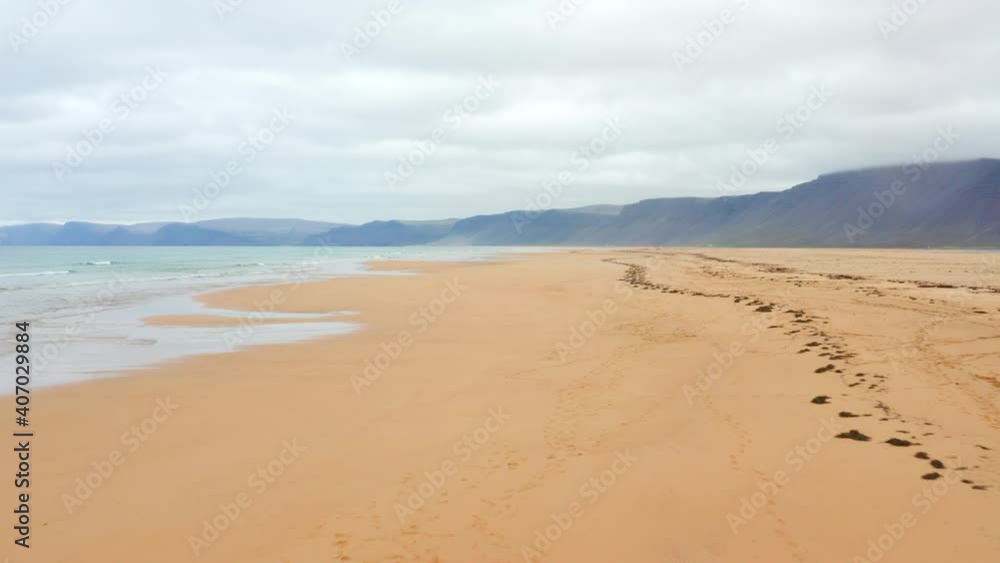 Group of People walking on orange red sand Beach along Ocean Waves Aerial Shot on Iceland Rauðisandur Group of People walking on orange red sand Beach along Ocean Waves Aerial Shot on Iceland Rauðisandur