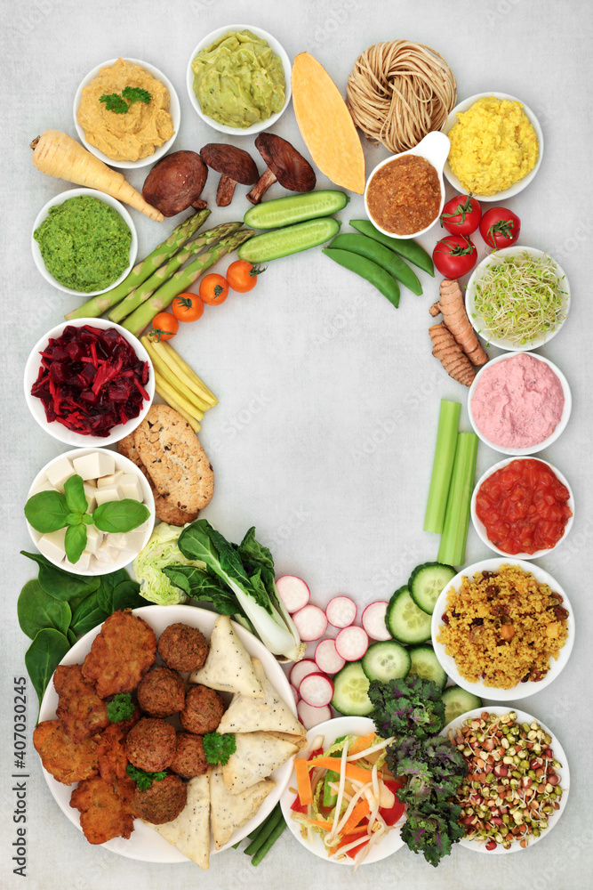 Vegan health food for a healthy diet with tofu bean curd, balls, bajis and samosas, vegetables, dips, grain and cereal products. Health foods for ethical eating. Background border on mottled grey.  