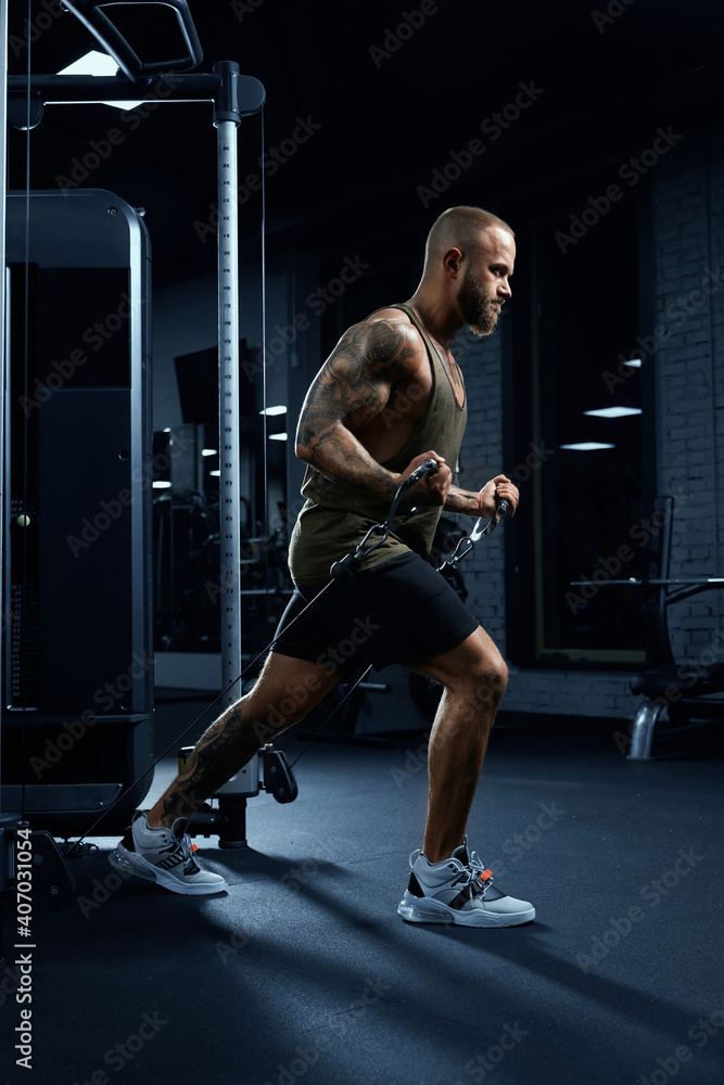 Tattooed bodybuilder doing crossover chest exercise. Tattooed bodybuilder doing crossover chest exercise.