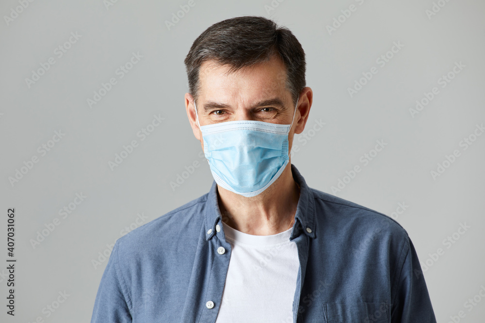 Senior wearing a protective face mask isolated on gray background in studio Senior wearing a protective face mask isolated on gray background in studio