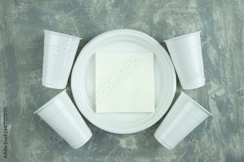 plastic dishes on a concrete background. plastic plates, forks, knives, glasses.