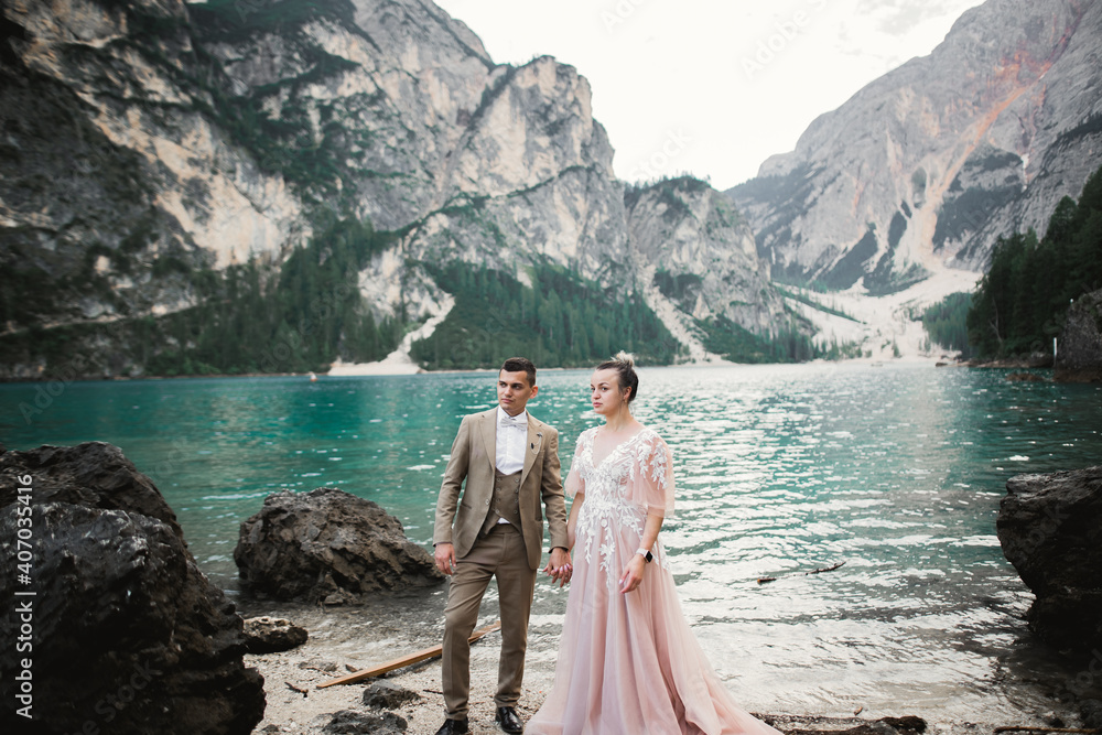 Young couple near lake Karersee, Italy. Holding hands at the stone at lake