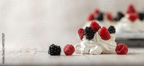 Delicious homemade meringue cake "Pavlova" with fresh raspberries and blackberries on a wooden background. Close-up.
