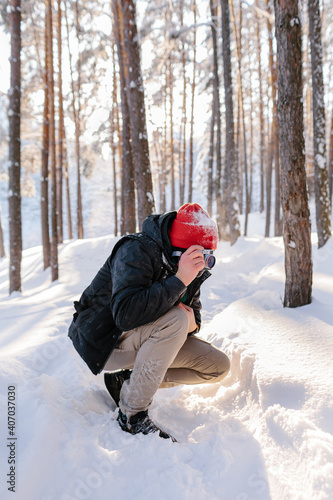 Young man takes photos in winter forest