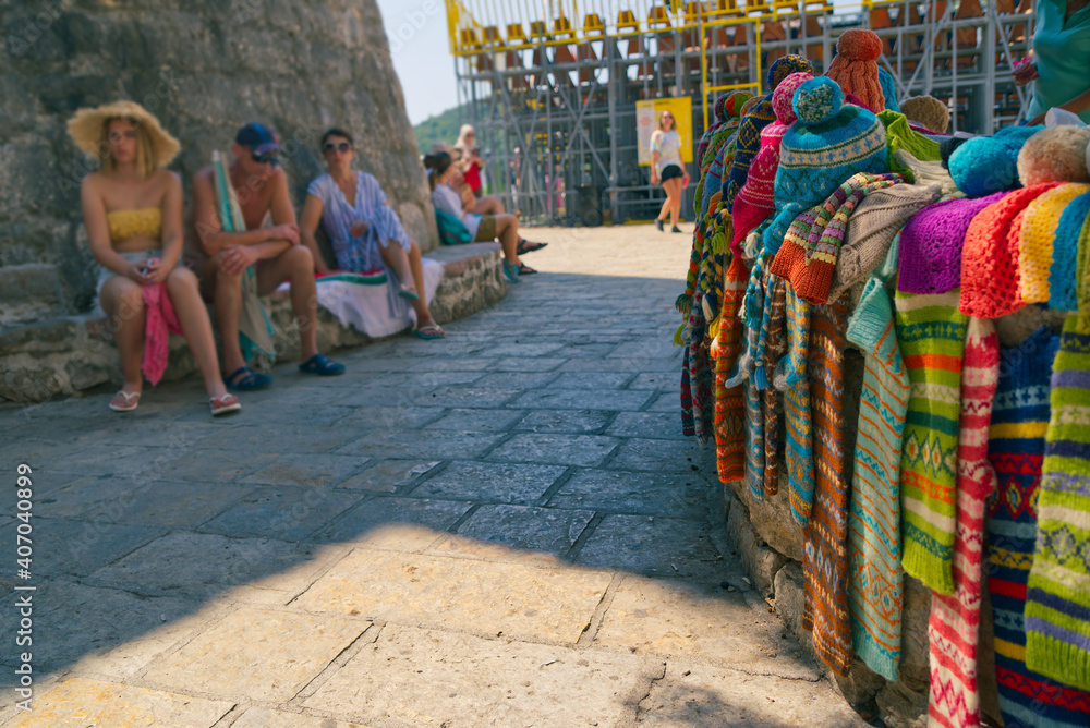 Funny image from the summer vacation in city. Stall with winter hats in the center of the summer resort in hot summer time. Family vacation in Croatia. Tourists tired of heat in the background.