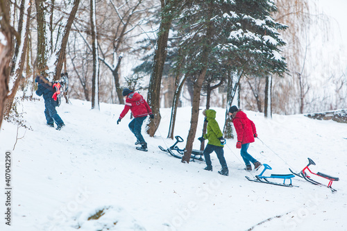 Lviv, Ukraine - January 5, 2019: kids boys friends pulling sledge to the snowed hill