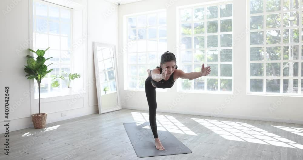 Beautiful Asian woman in sportswear is practicing yoga at home. Beautiful Asian woman in sportswear is practicing yoga at home.