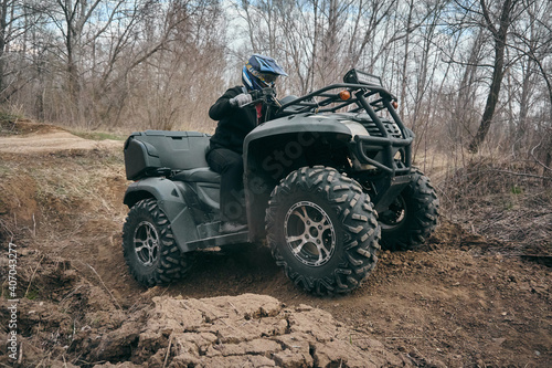Man driving a quad bike rides on hilly surface, autumn forest, tourist trip