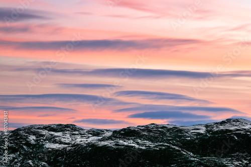 The evening sky. Lenticular clouds over the snowy hills of the Arctic. Kola Peninsula.